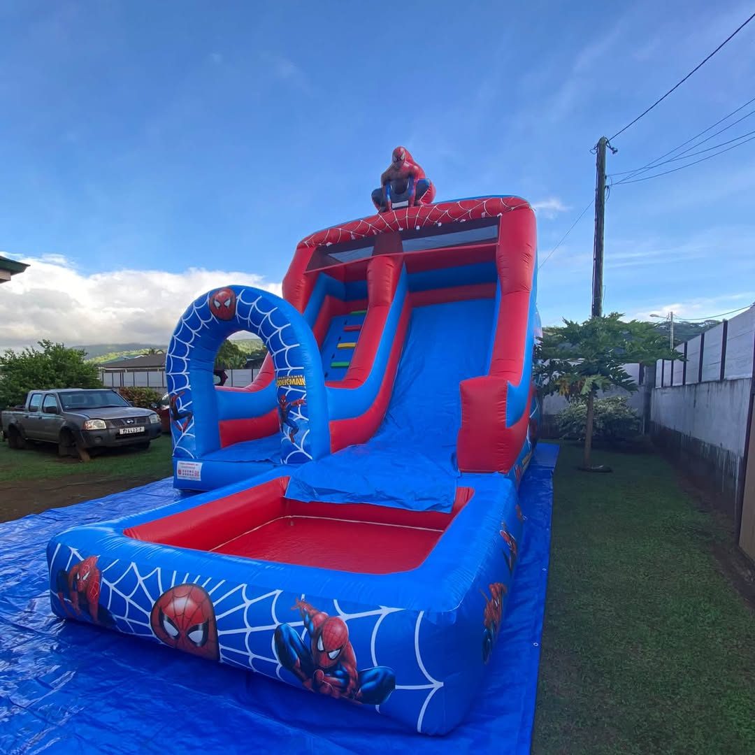Toboggan aquatique rouge et bleu décor araignée installé dans un jardin à Tahiti